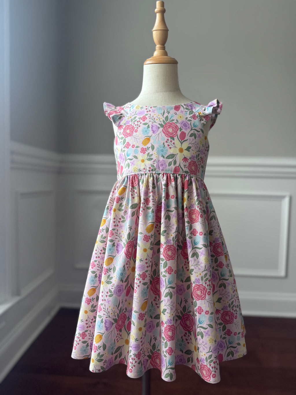 Floral dress on a mannequin against a neutral wall.