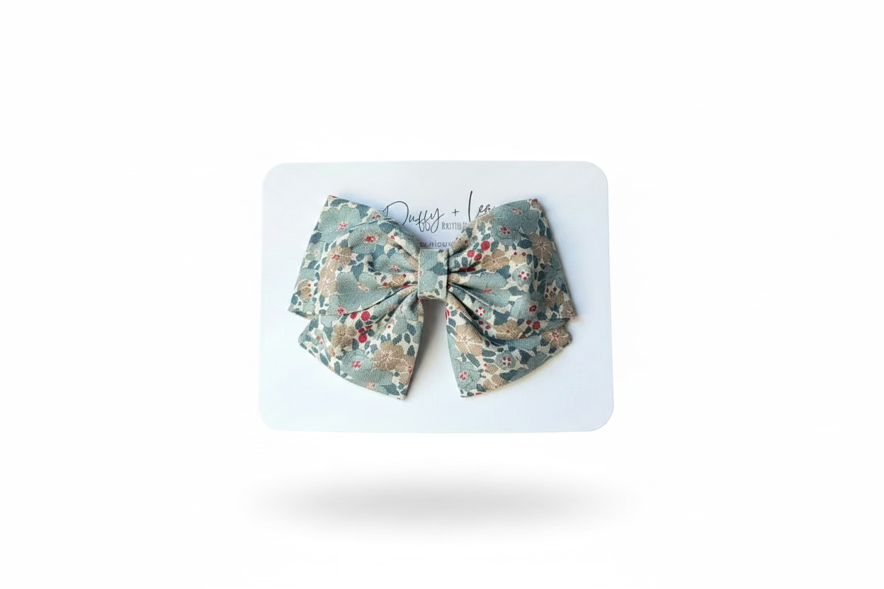 Floral-patterned bow held on a white card against a neutral background